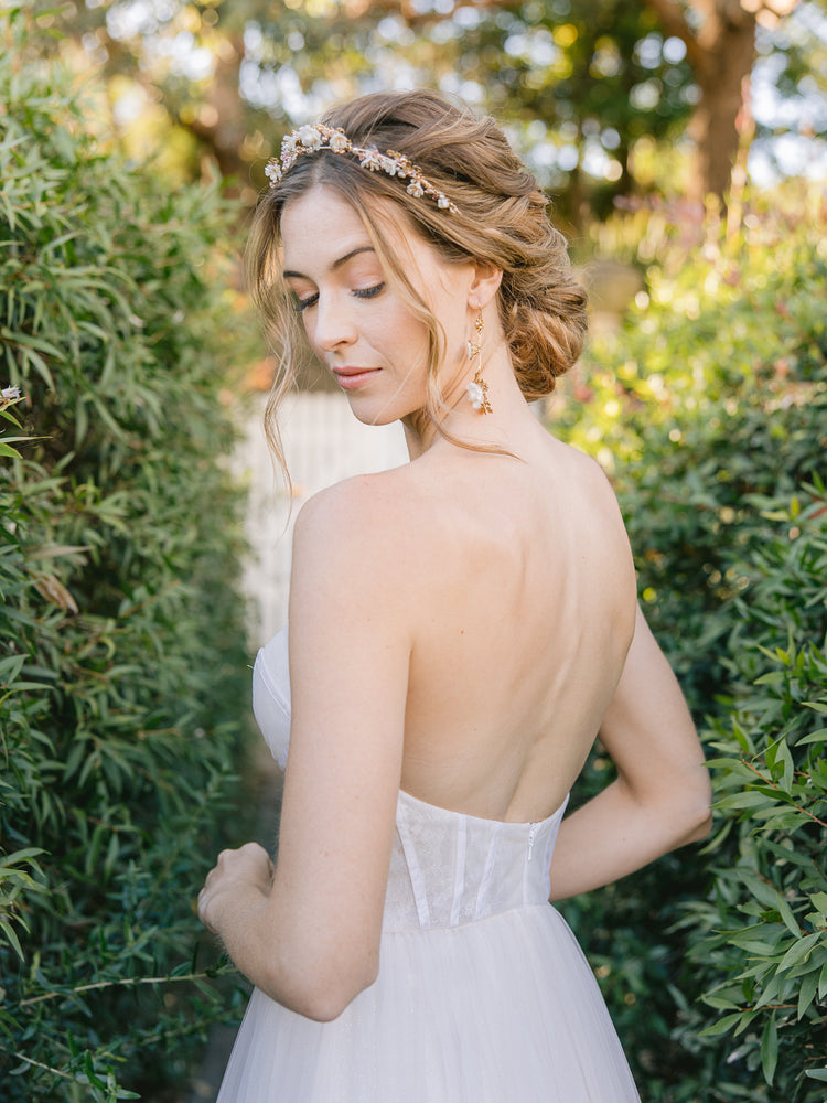 
            
                Load image into Gallery viewer, bride wearing a floral wedding crown with blush pearls with an updo and floral gold drop earrings
            
        