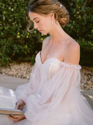 
            
                Load image into Gallery viewer, bride reading a book in a blush tulle wedding gown and wearing silver crystal long drop earrings with romantic updo and silver headpiece
            
        