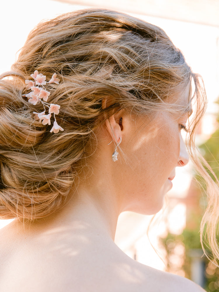 Bride wearing crystal drop earrings and pink flower hair pins