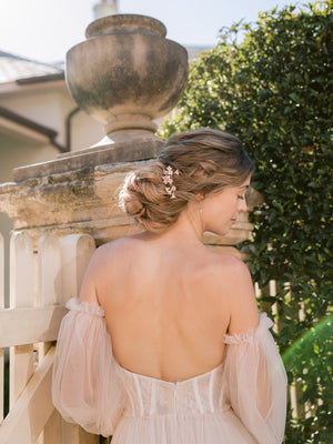 Bride in a blush romantic wedding gown, wearing blush flower hair pins and silver crystal drop earrings 