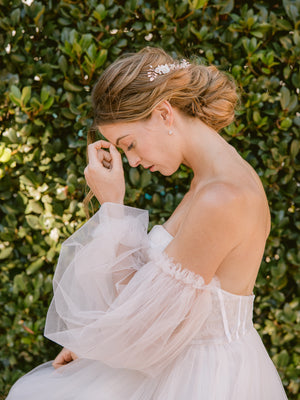 
            
                Load image into Gallery viewer, Bride wearing a puffy sleeved blush tulle gown and rose gold hair accessories and jewellery with crystals and pearls
            
        
